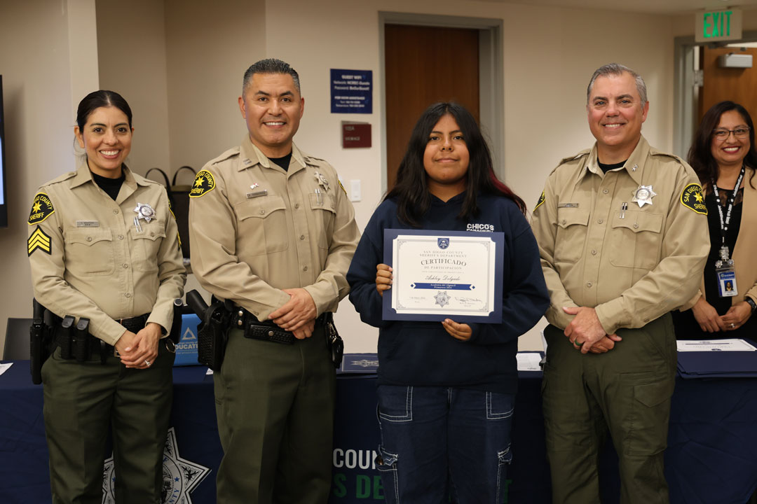 Three deputies with a spanish academy student holding a certificate.