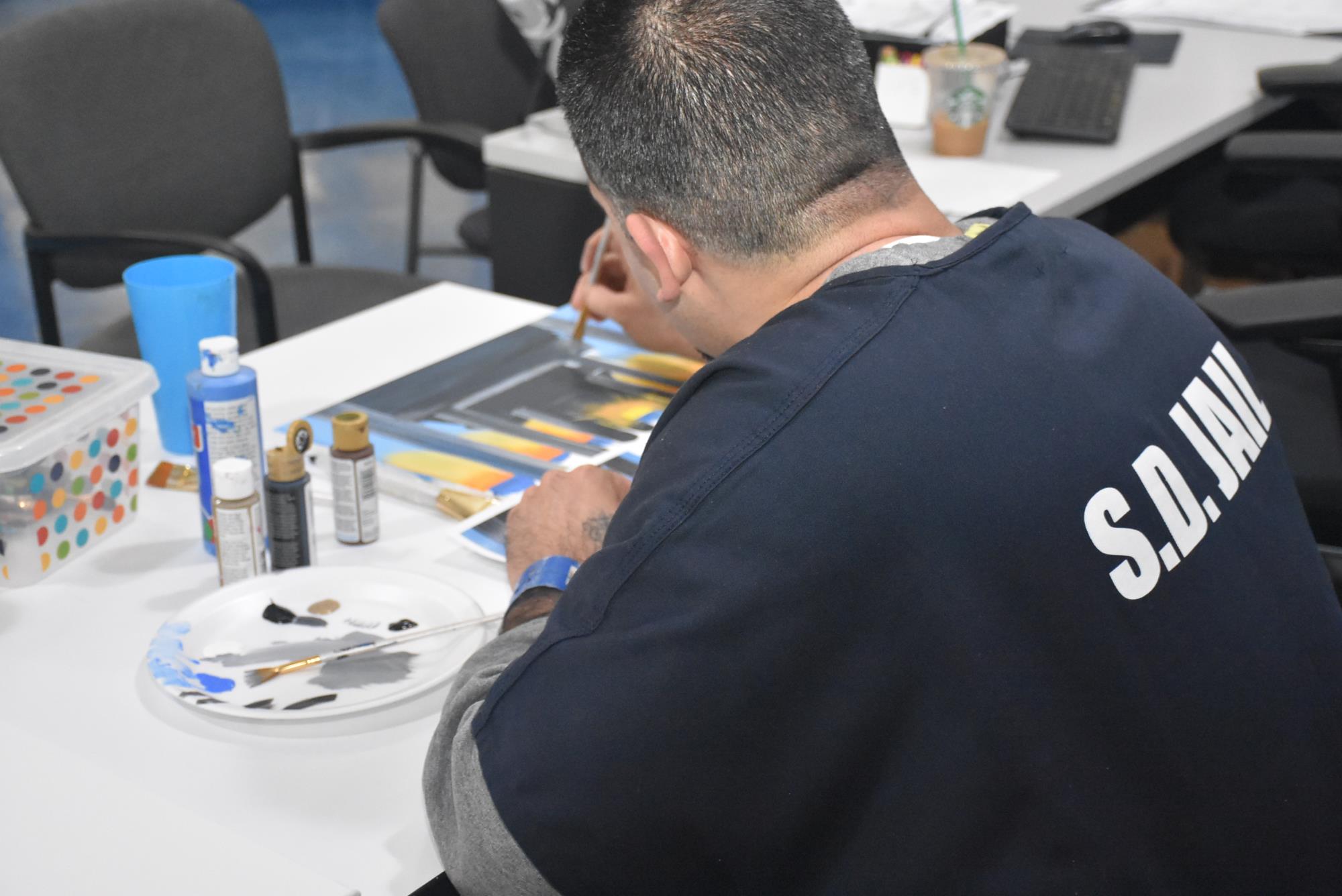 Male student painting a picture at a desk